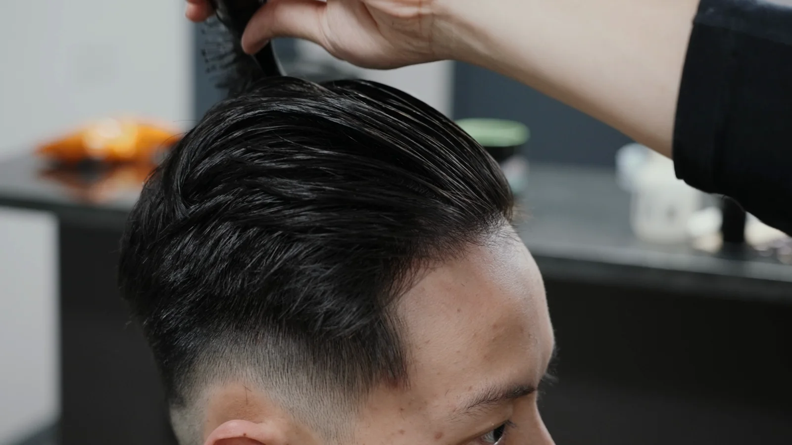 A barber shaping the final details of a haircut