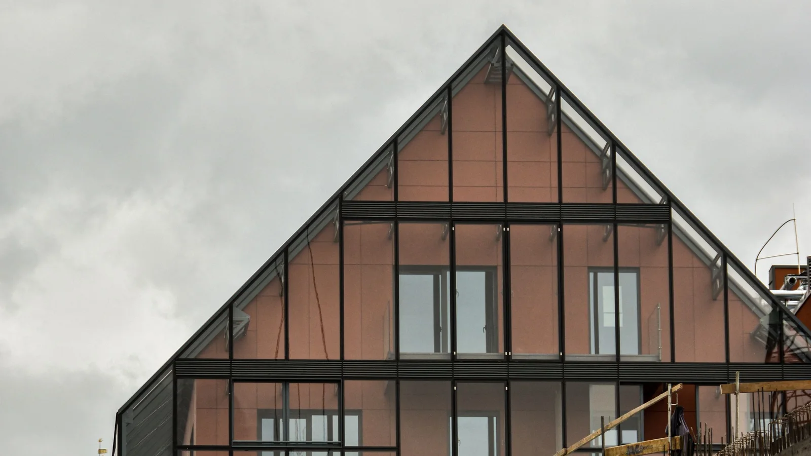 A modern building rising beside an active construction site