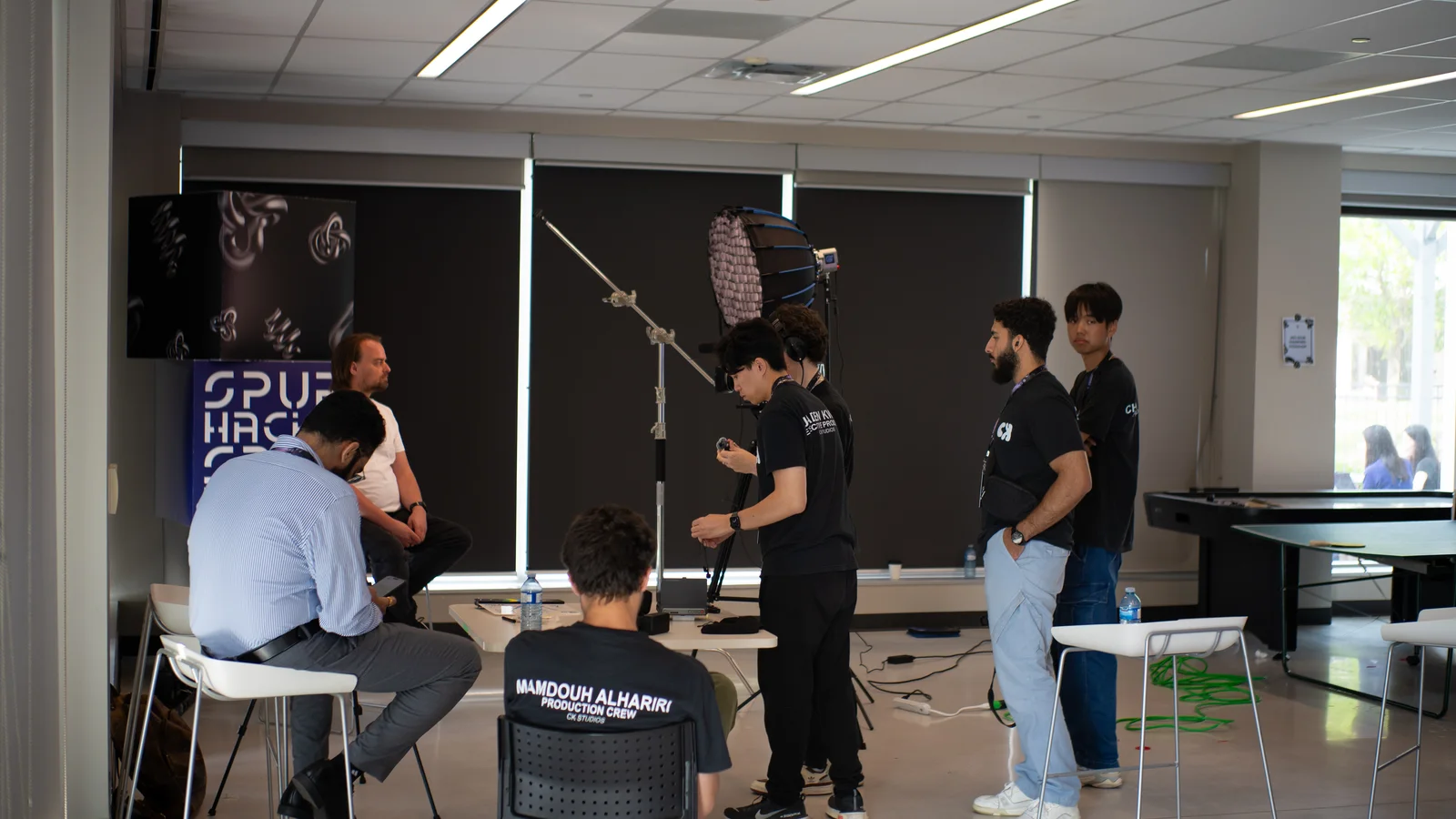 A CK crew filming a seated interview with professional lighting and audio
